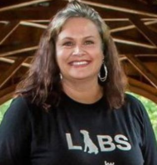 A smiling woman wearing a black shirt with a dog silhouette and the word LABS.