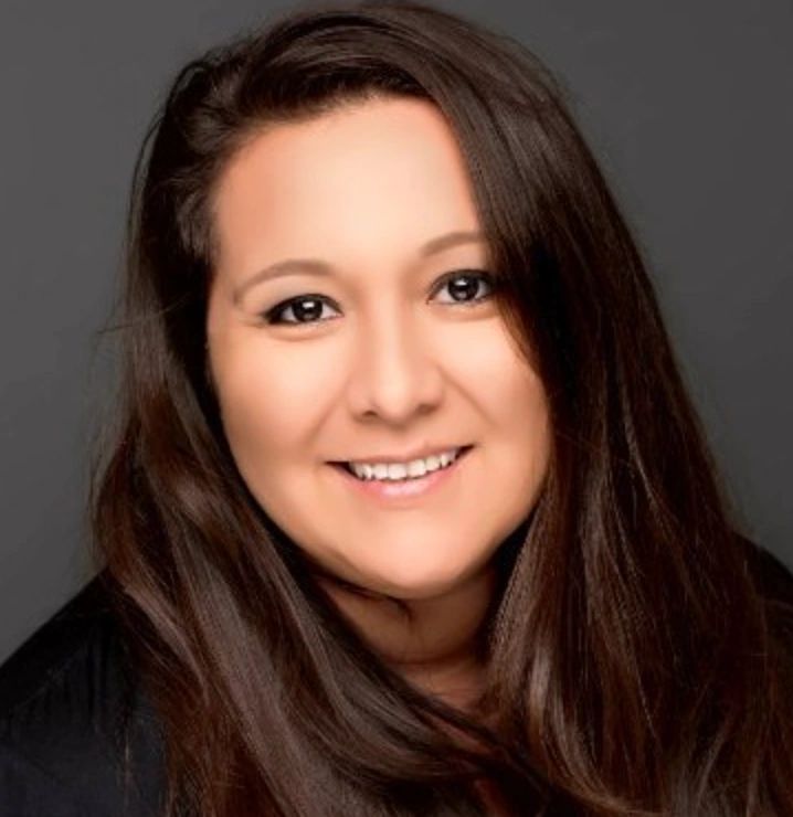 Smiling woman with long brown hair against a dark background.